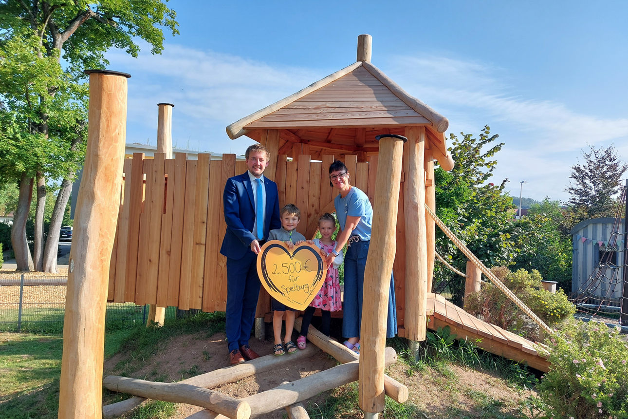Zwei Kinder und zwei Erwachsene auf einer Spielburg im Kindergarten