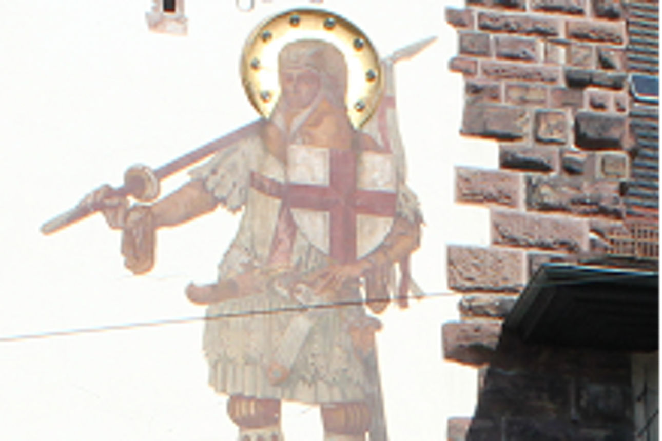 Gemälde eines Heiligen mit Schwert und Drachen an einer Steinmauer mit weißem Putzfeld.