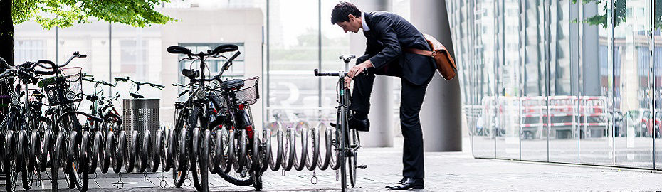 Ein Mann im Anzug lehnt sich lässig an ein Fahrrad