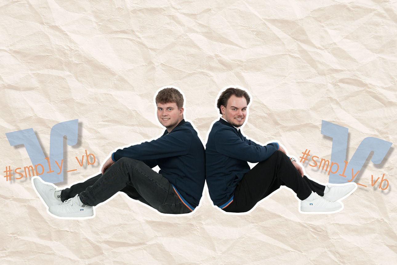 Zwei Männer sitzen Rücken an Rücken auf blauen VR-Bank-Sitzwürfeln vor hellem Hintergrund.