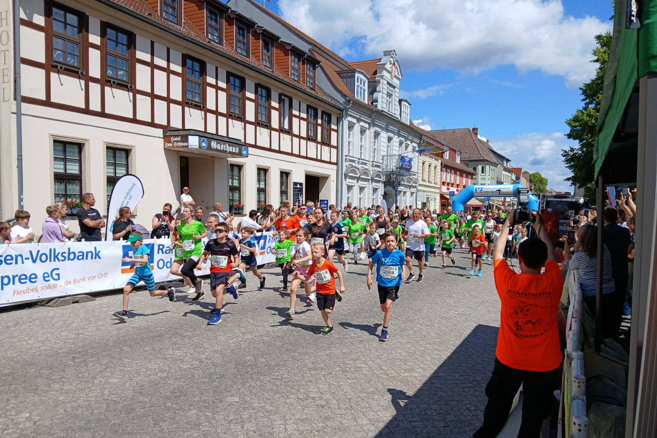 Kinder laufen bei Altstadtlauf an Zuschauern und Gebäuden vorbei