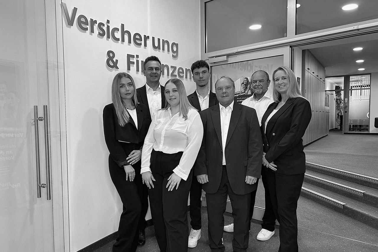 Fünf Personen in formeller Kleidung stehen nebeneinander und blicken in die Kamera.