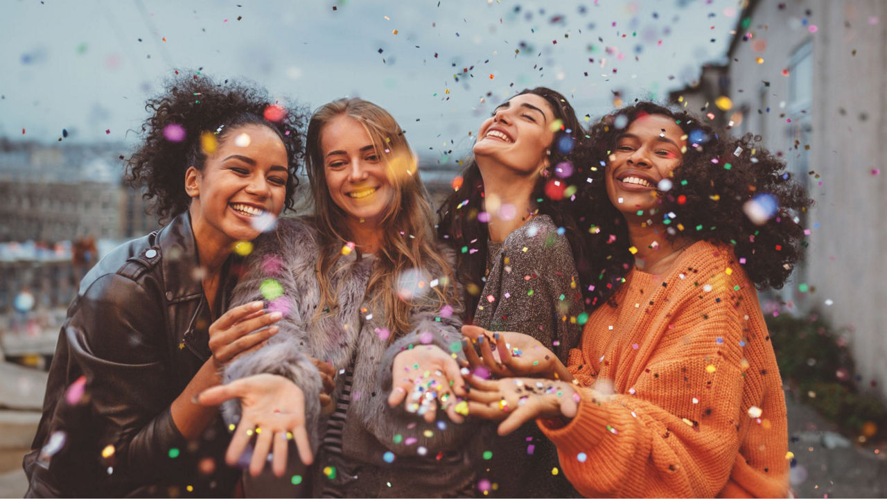 Vier junge Frauen feiern mit Konfetti und sind glücklich