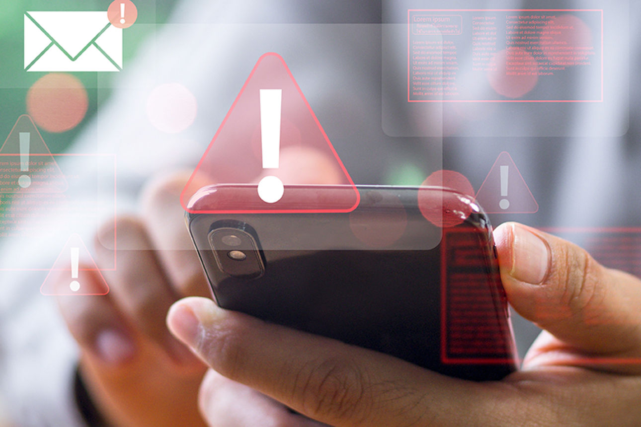 Mann bedient Handy und Warnzeichen werden angezeigt
