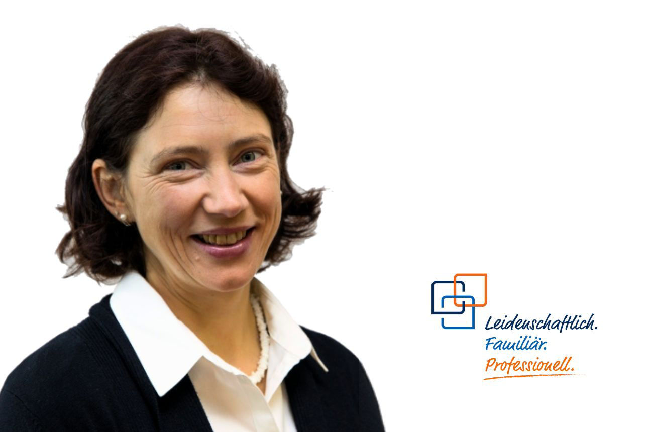 Porträt von Stephanie Karl, einer lächelnden Frau mit dunklen Haaren, weißer Bluse und schwarzer Strickjacke. Daneben das Firmenlogo und der Slogan "Leidenschaftlich. Familiär. Professionell."