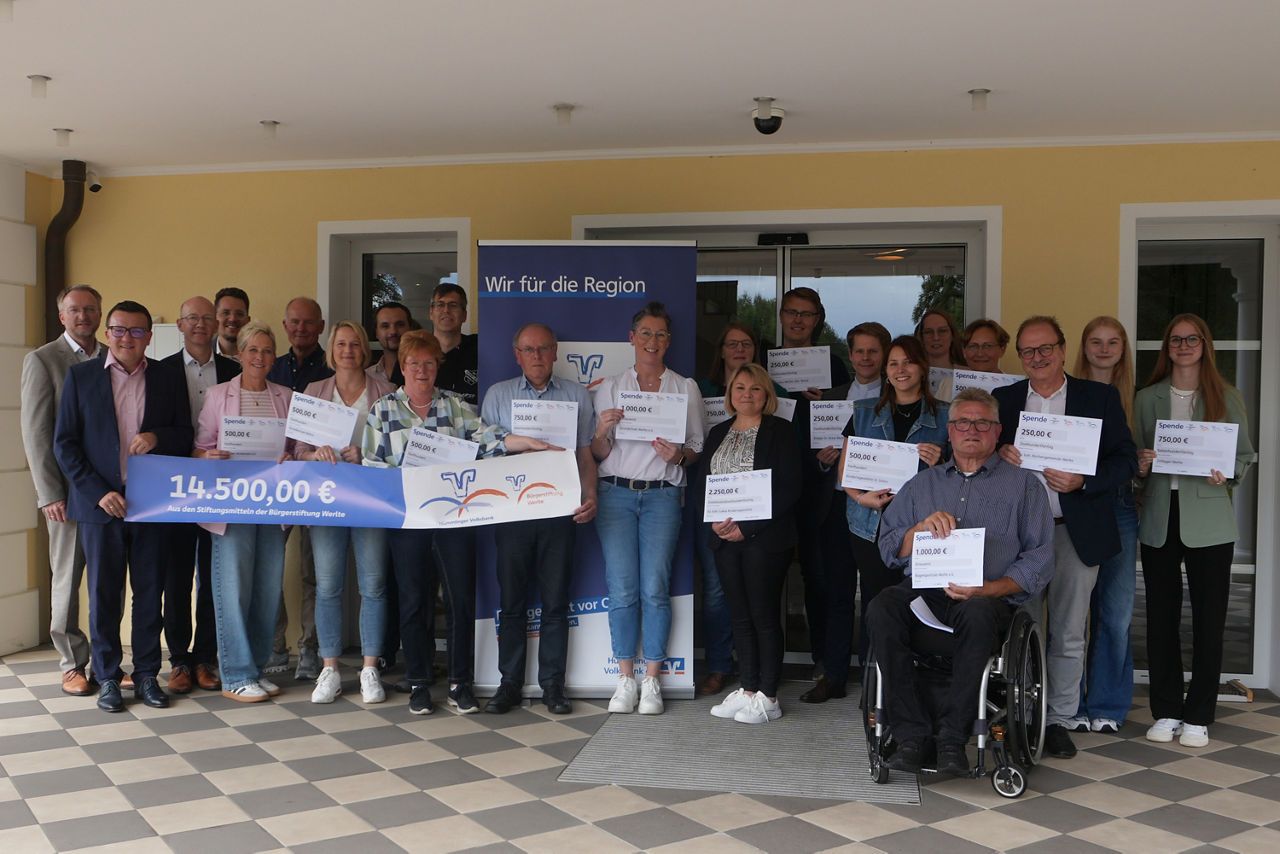 Eine bunt gemischte Gruppe von Personen, die stolz ihre Zertifikate vor einer großen Treppe präsentieren. 