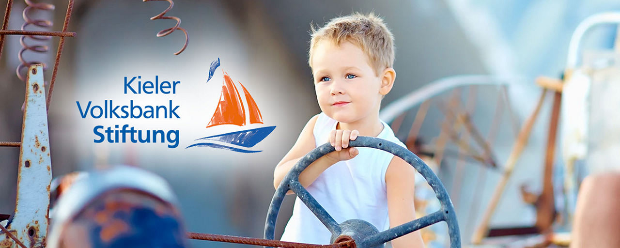 Junge am Steuer Boot mit Logo Kieler Volksbank Stiftung