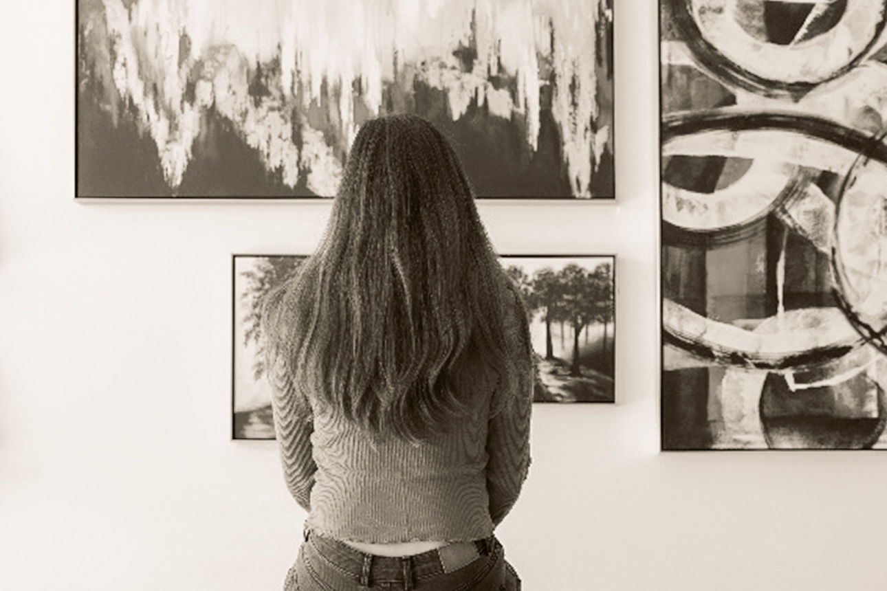 Eine Dame sitzt vor einer Wand mit Bildern