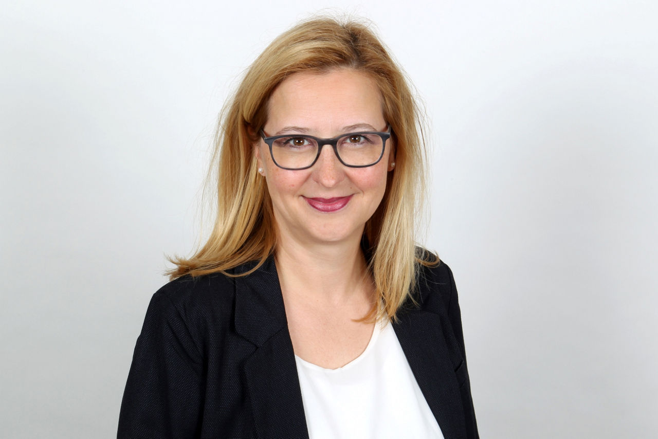 Eine lächelnder Frau schaut in die Kamera.