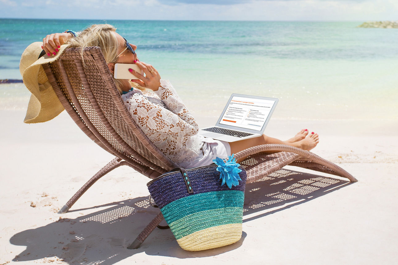 Frau entspannt auf Strandliege, telefoniert und hat einen Laptop auf den Beinen.