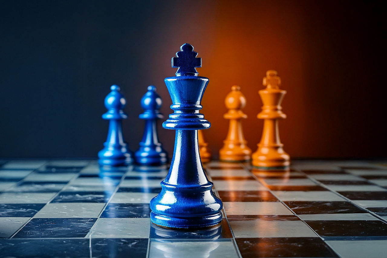 Das Bild zeigt blaue und orange Schachfiguren auf einem Schachbrett.