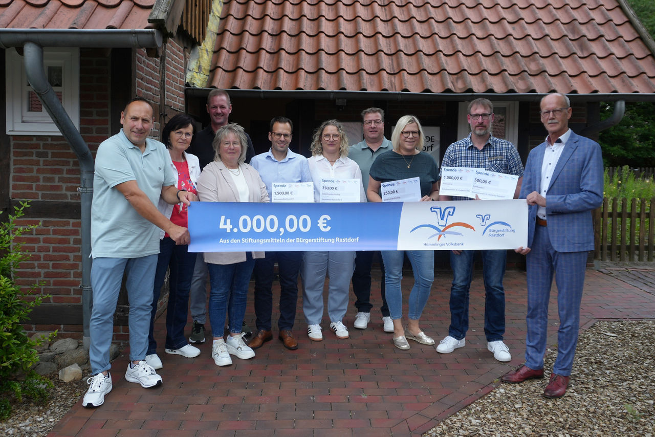 Eine bunt gemischte Gruppe von Menschen hält stolz eine Schleife