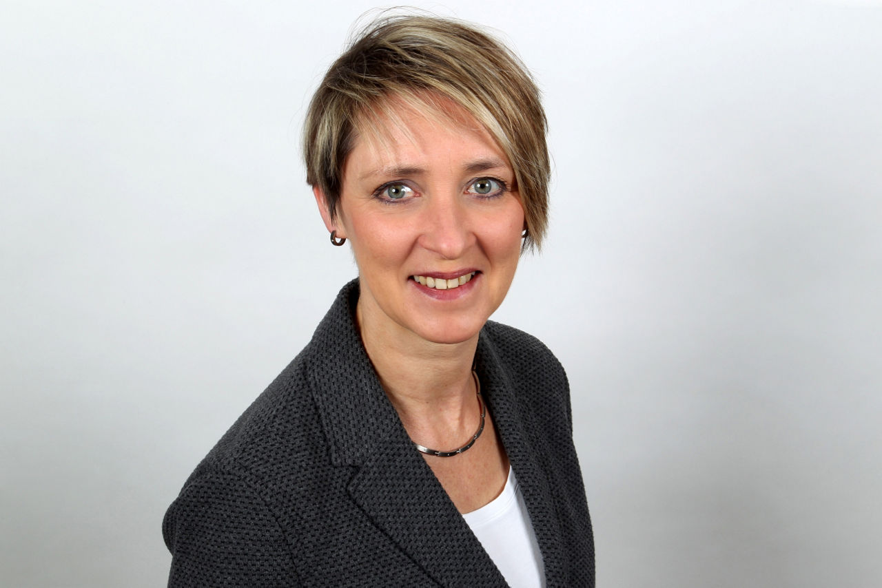 Eine lächelnder Frau schaut in die Kamera.