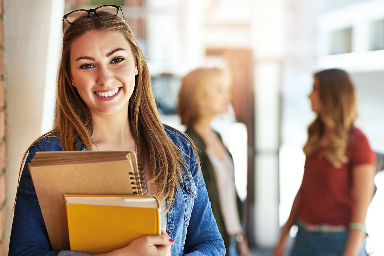 Mädchen lächelt und hat zwei Bücher in der Hand