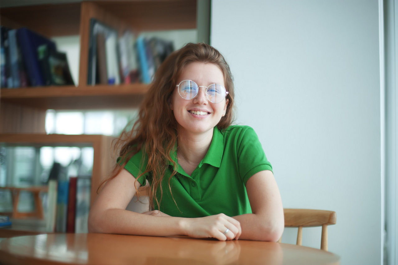 Junge Frau sitzt an einem runden Tisch in der Universitätsbibliothek.