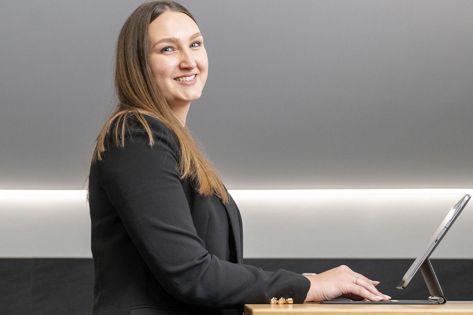 Junge Frau sitzt vor einem Tablet in einem modernen Raum