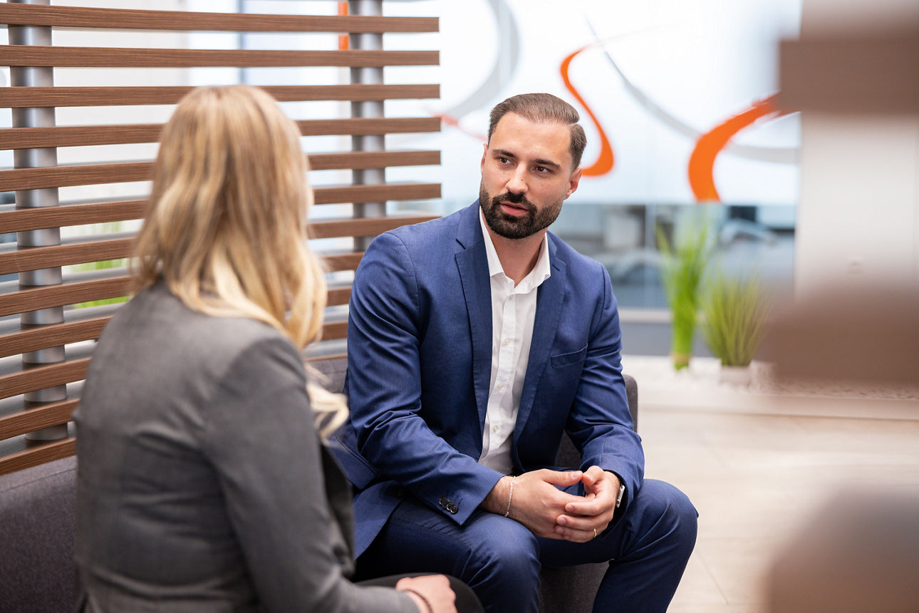 Mann im Gespräch mit einer Kollegin in einer Bank