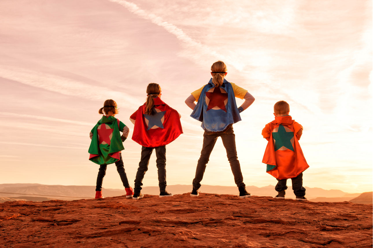Vier Kinder mit Superheldenumhängen
