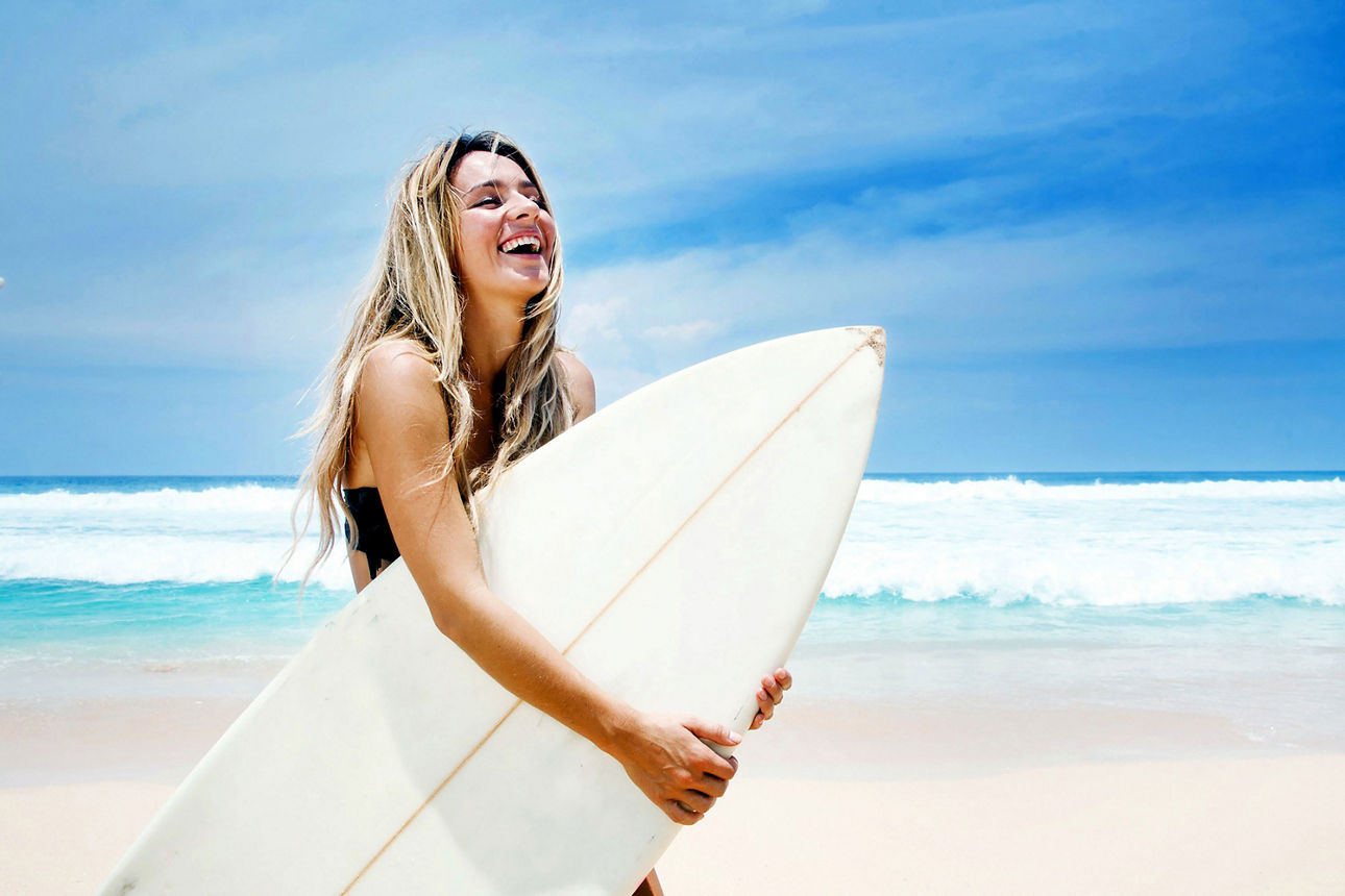  Eine Frau mit Surfboard am Strand
