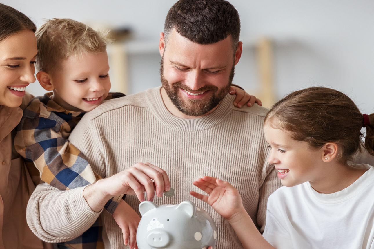 Ein lächelnde Familie, die eine Münze in einen Sparschwein tun.