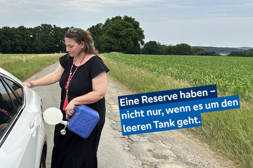 Eine Frau im schwarzen leid befüllt den Tank ihres Autos mit Tank aus einem Kanister