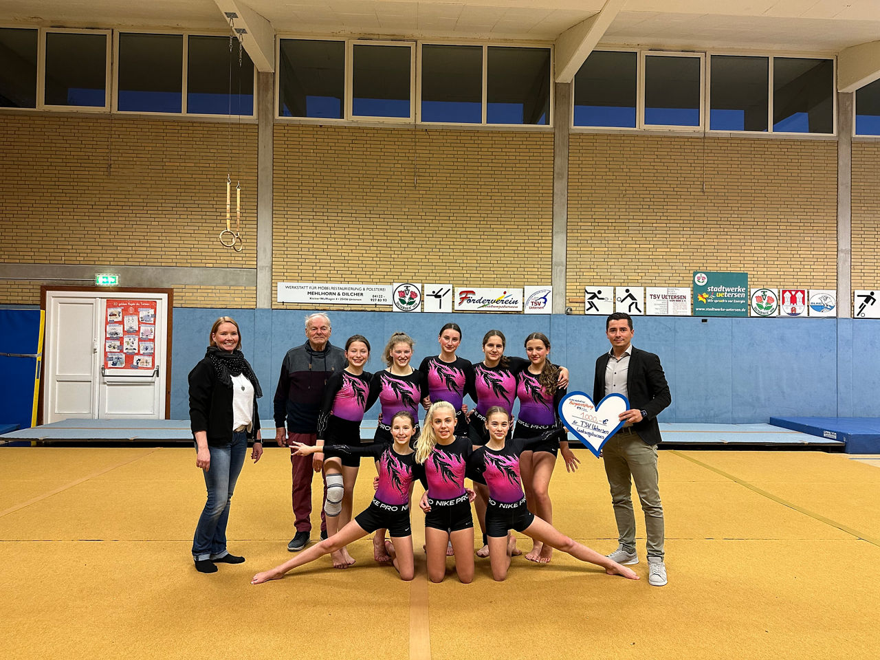 8 Turnerinnen mit 2 Trainerinnen vom TSV Uetersen und Regionalleiter Memet Deniz beim Scheckübergabetermin in Turnhalle