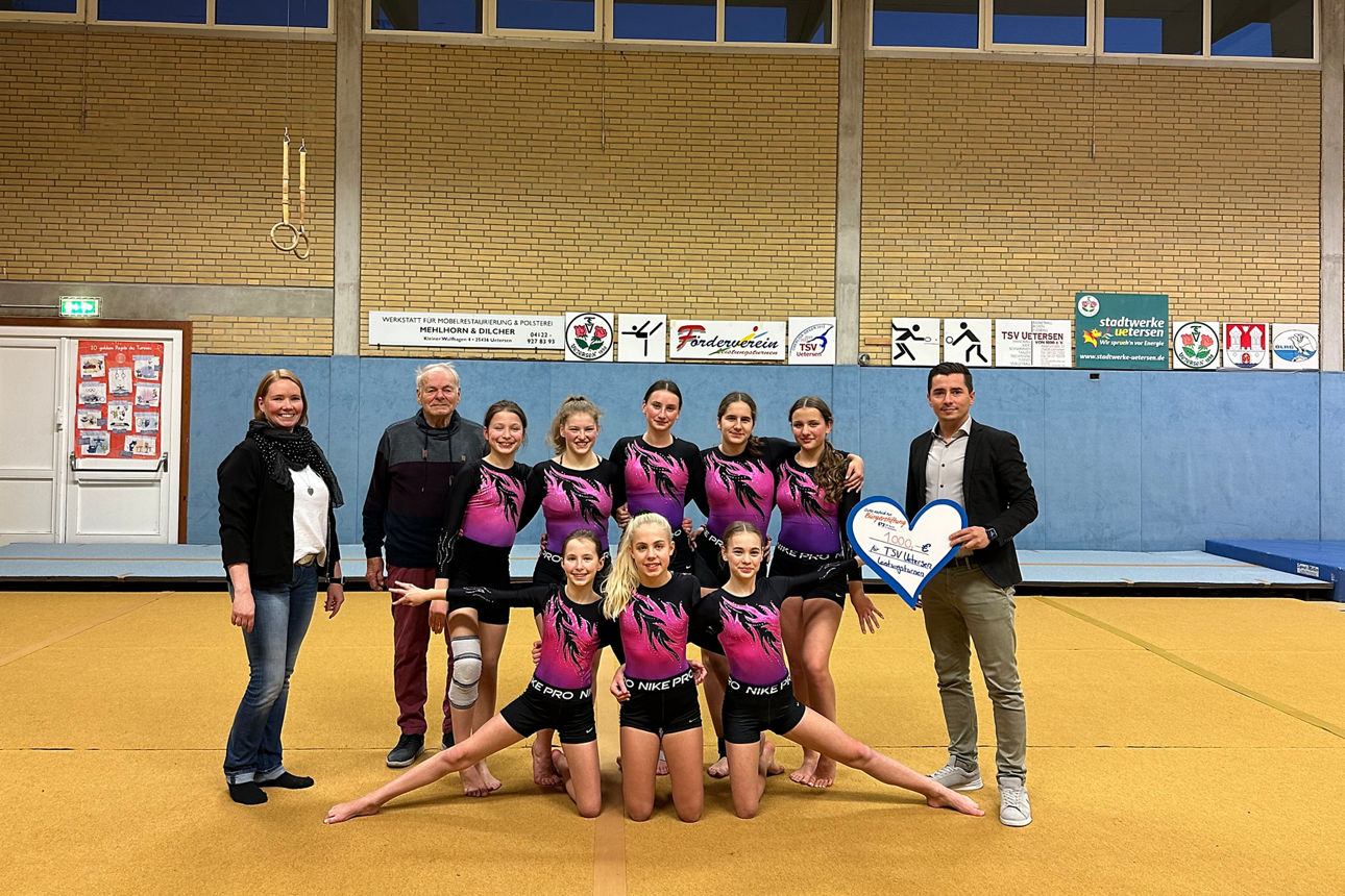 8 Turnerinnen mit 2 Trainerinnen vom TSV Uetersen und Regionalleiter Memet Deniz beim Scheckübergabetermin in Turnhalle