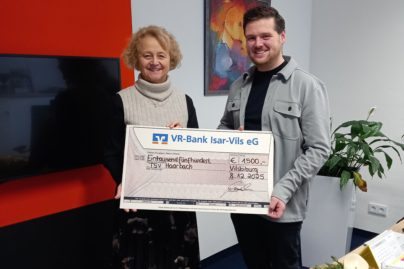 Eine Frau und ein Mann lächeln in die Kamera. Sie halten einen Riesenspendenscheck in der Hand.