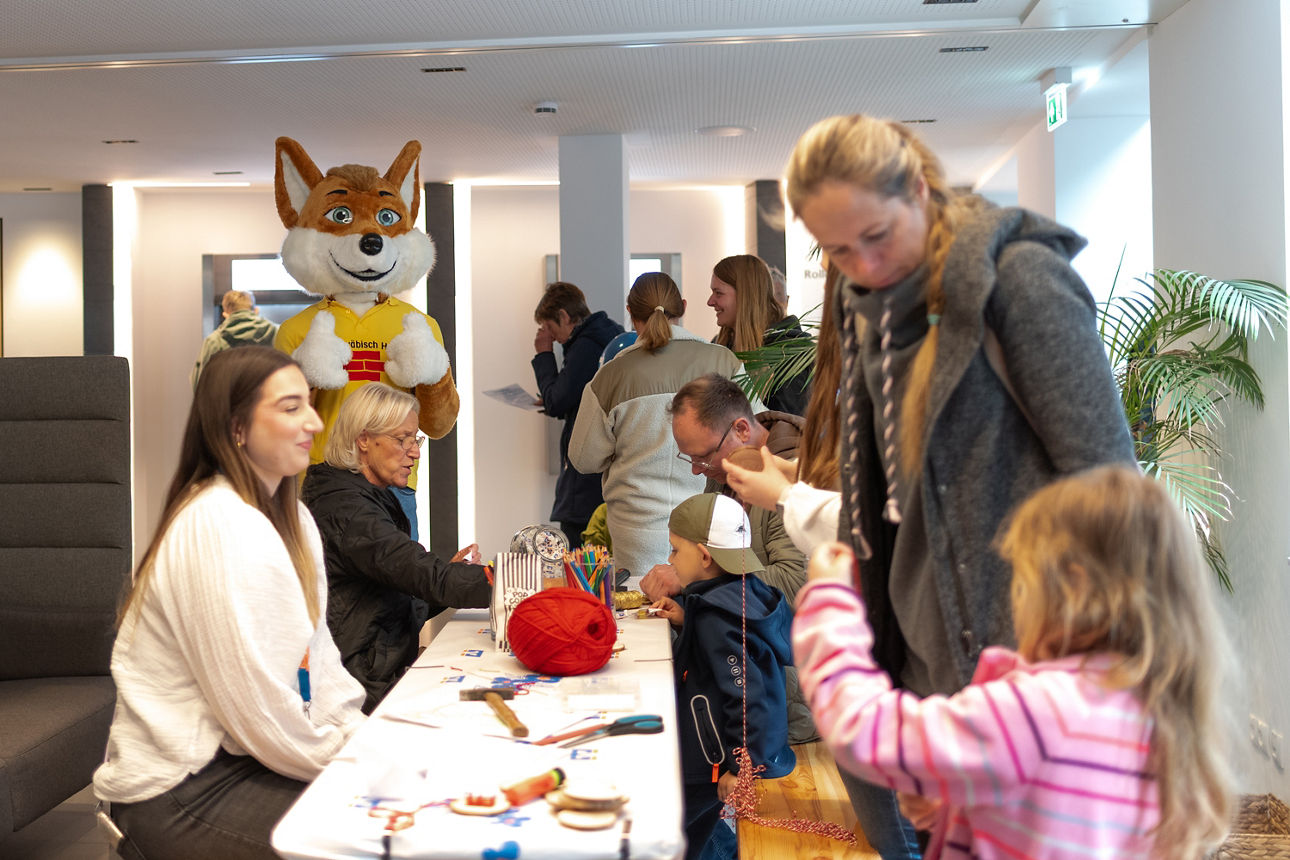 Kinder und Erwachsene sitzen an einem Tisch und basteln