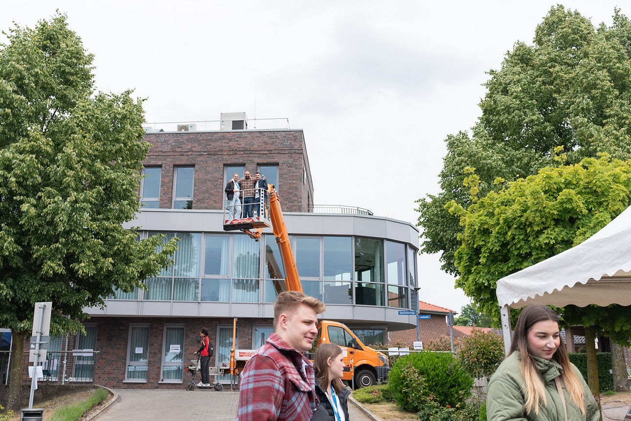 Drei Menschen auf einer Hebebühne vor der Volksbank Schermbeck