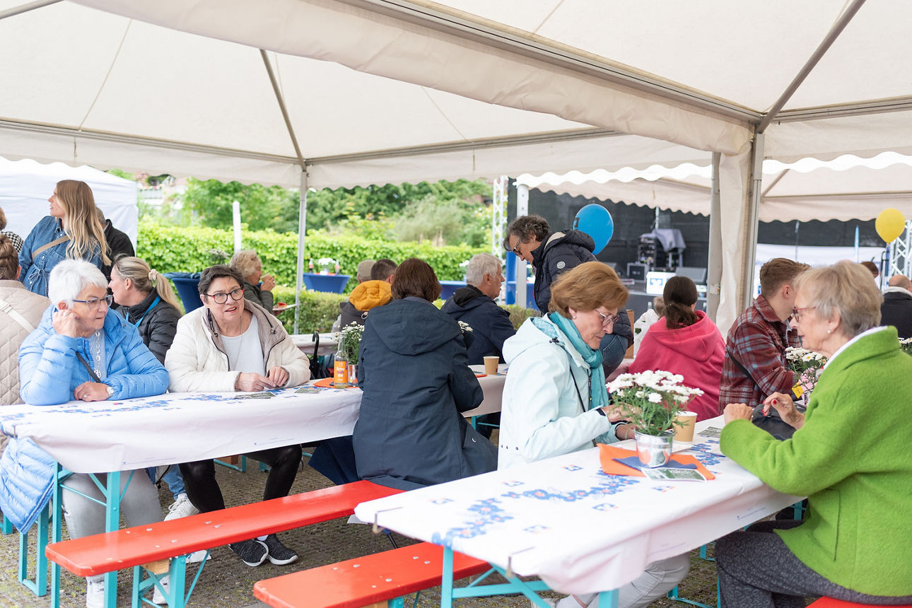 Einige Personen sitzen an Tischen unter Pavillions