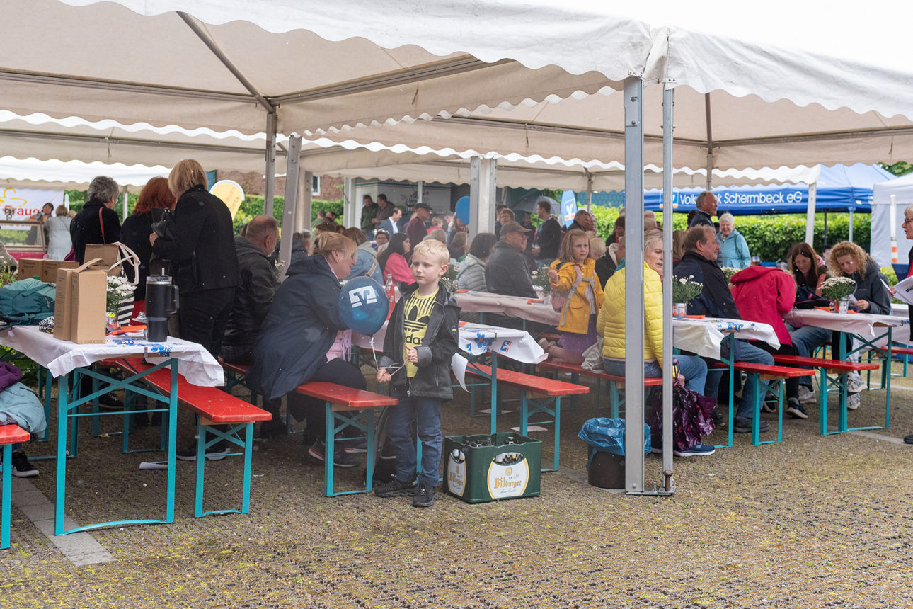 Viele Personen, sitzend an Tischen unter Pavillions