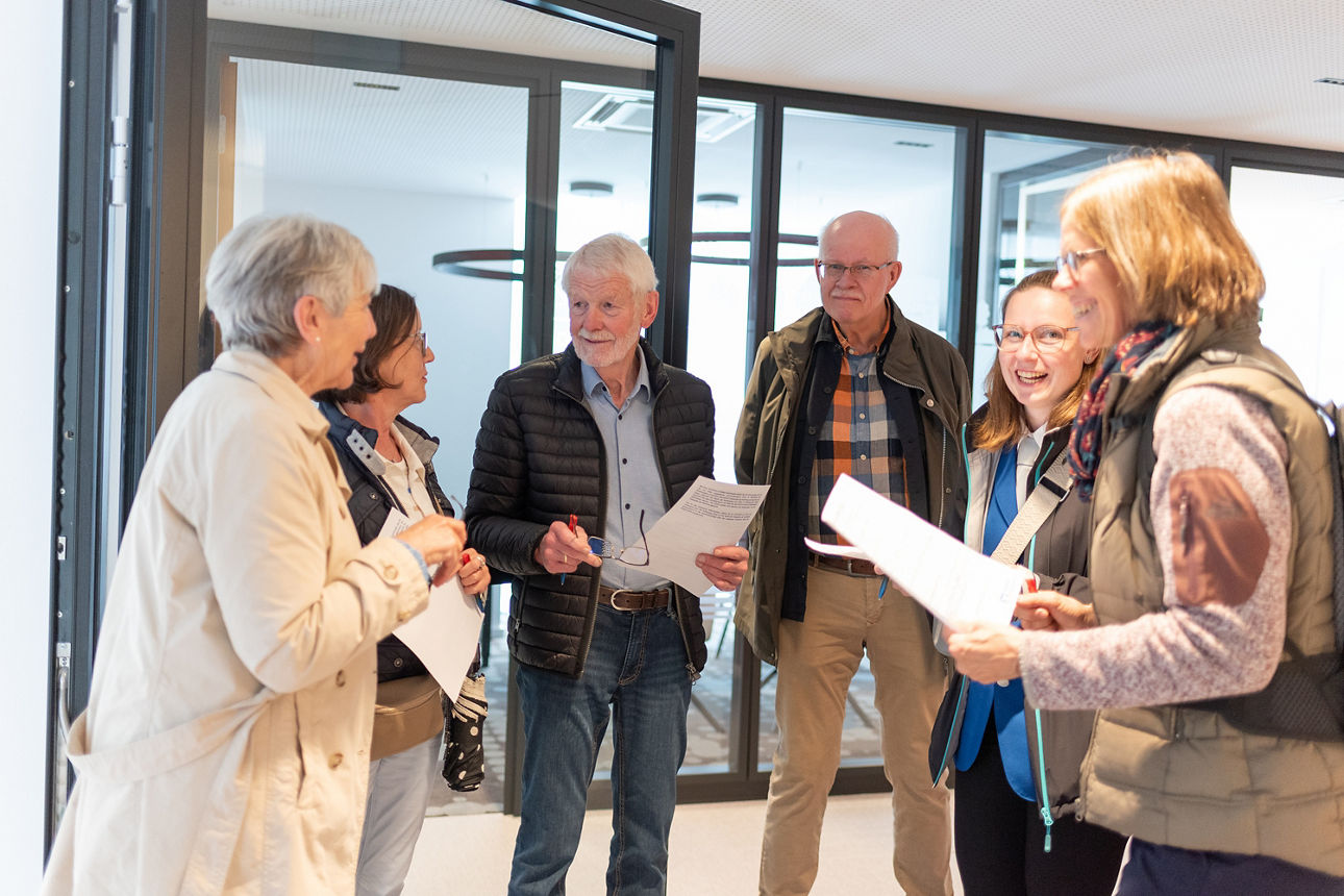 Sechs Personen im Halbkreis in der Volksbank Schermbeck mit Papieren in der Hand