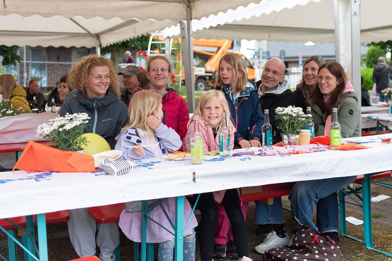 Personengruppe mit Kindern an einem Tisch sitzend