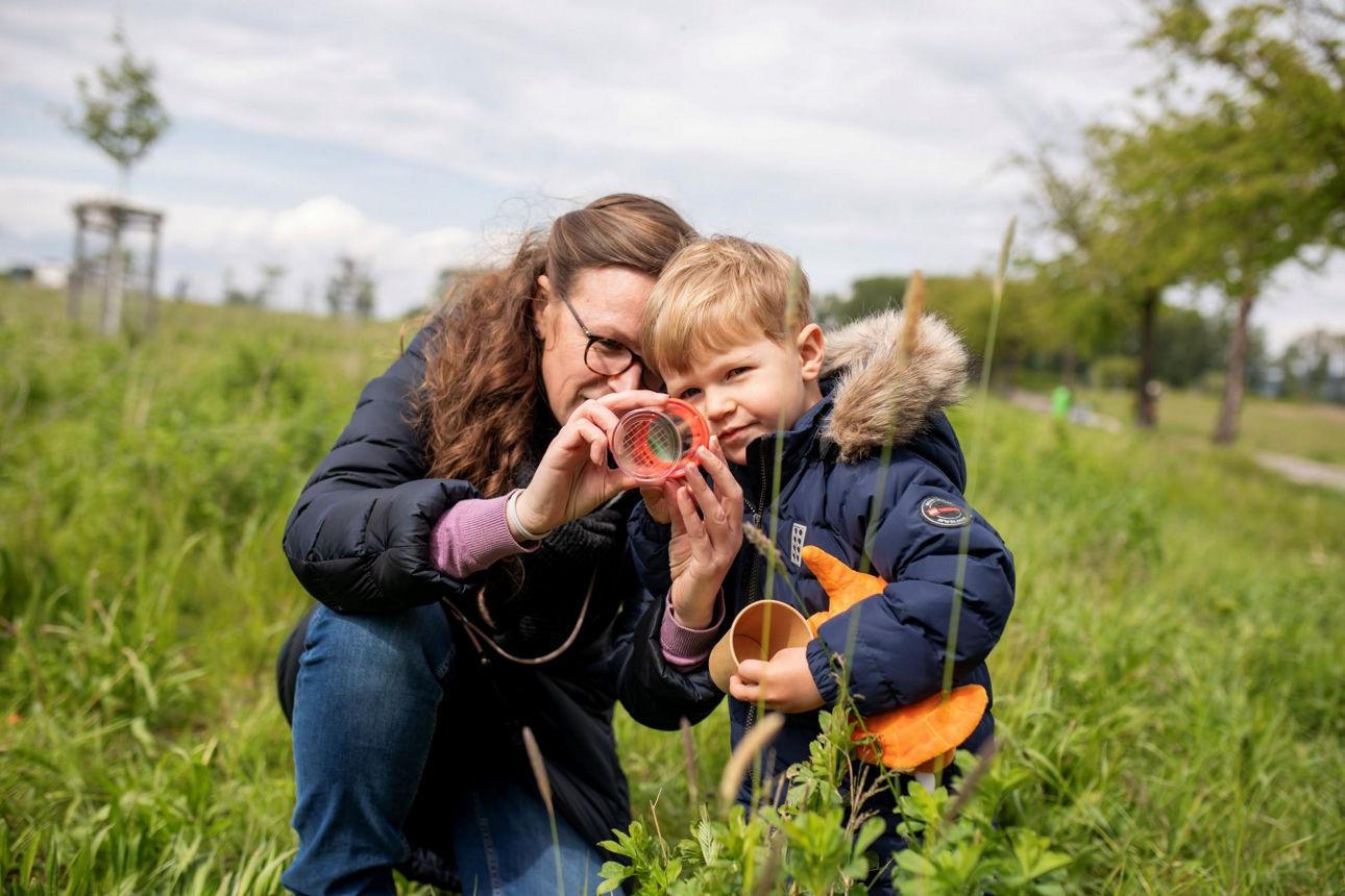 Frau mit Kind schauen sich Insekten an