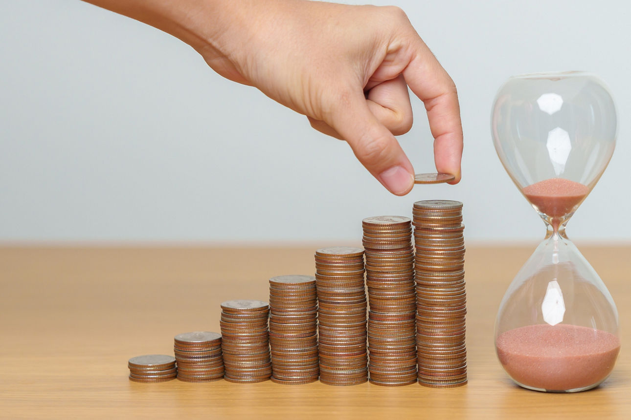 Zinskurve aus Münzstapel gebaut und am Ende steht eine Sanduhr