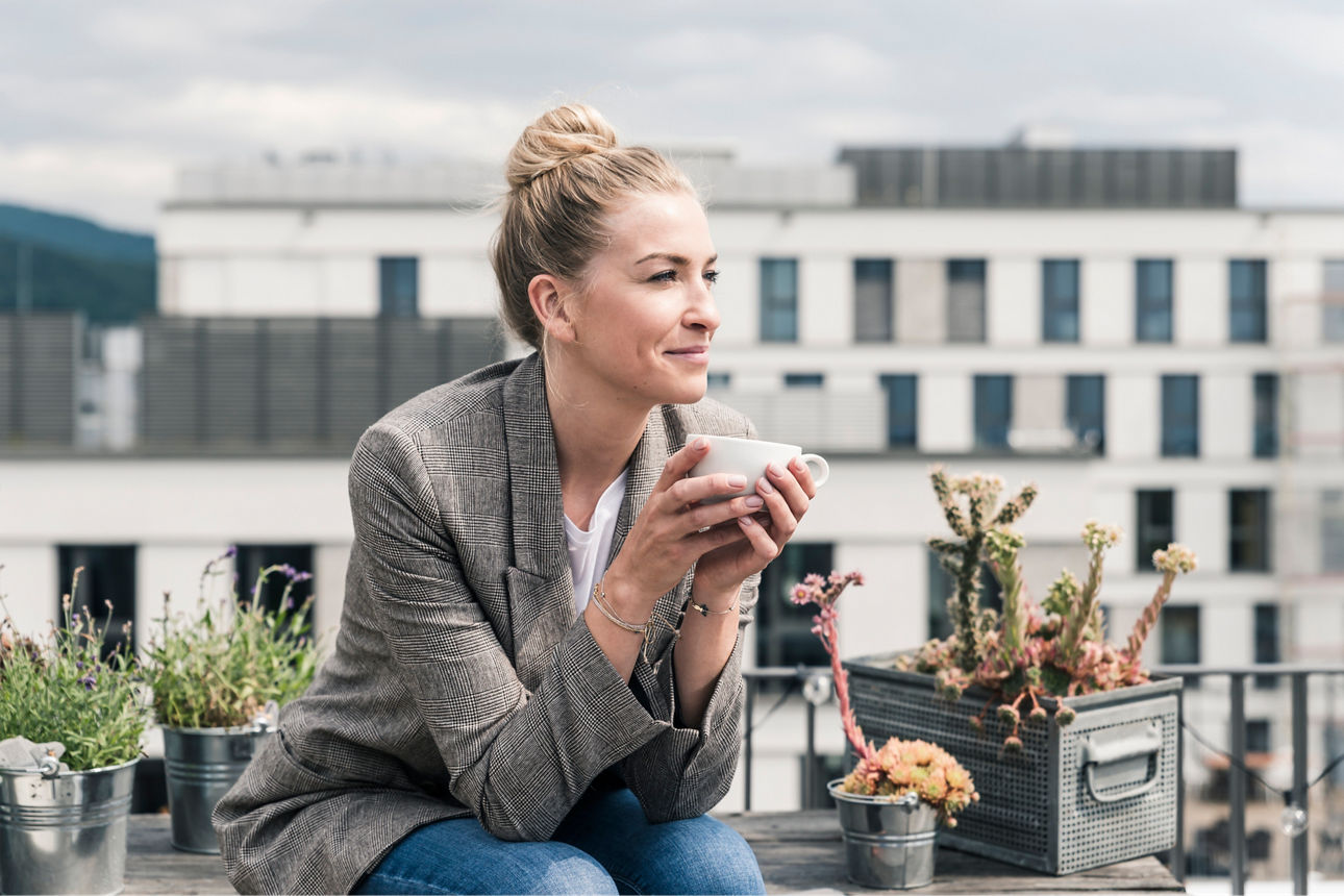Abbildung einer Dame, die gerade auf einer Dachterrasse ihren Tee genießt