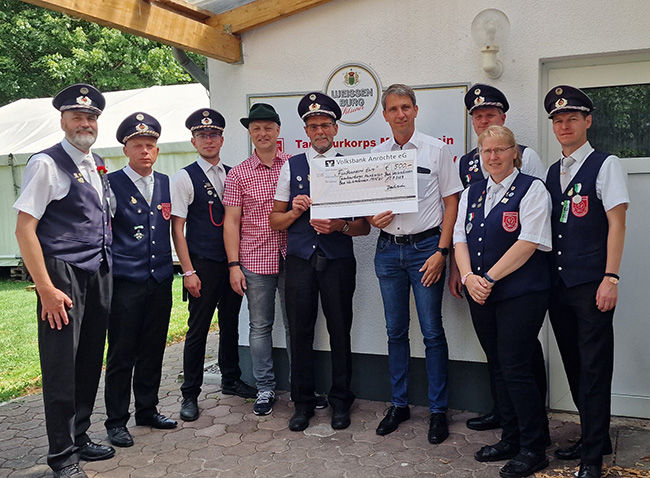 Menschen in Uniform, die zusammen mit einem Bankvertreter einen großen Scheck halten