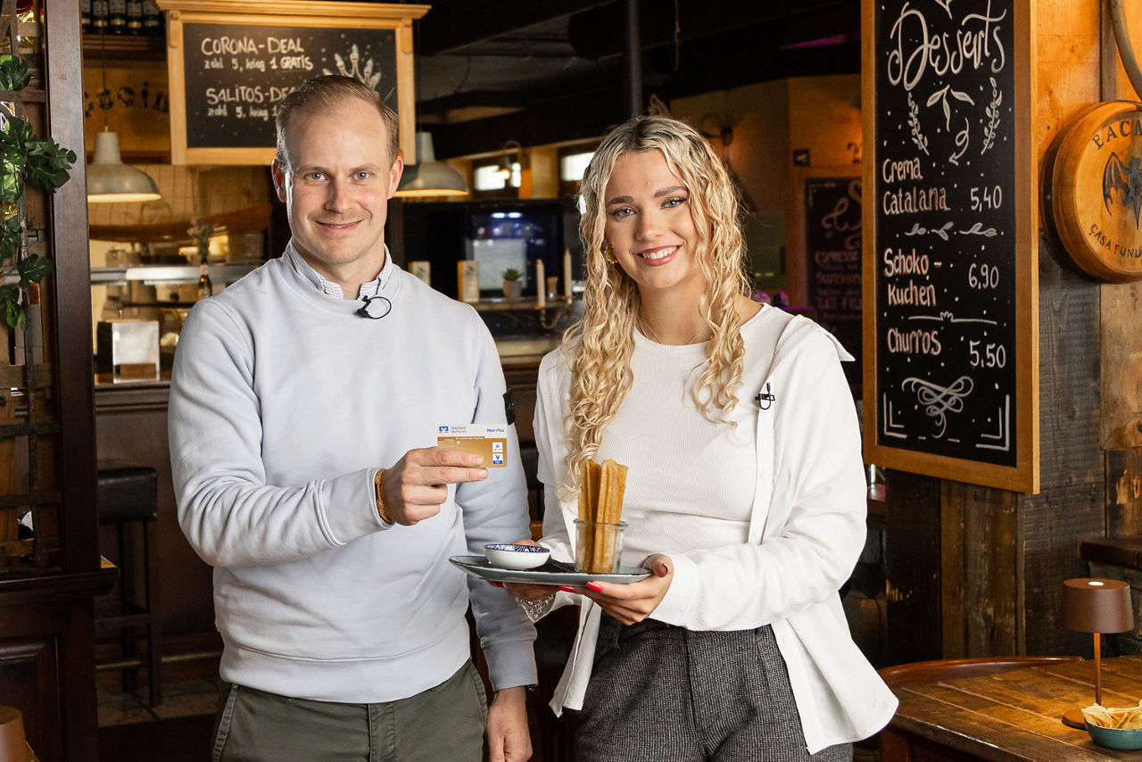 Zwei Personen halten die goldene girocard und Churros