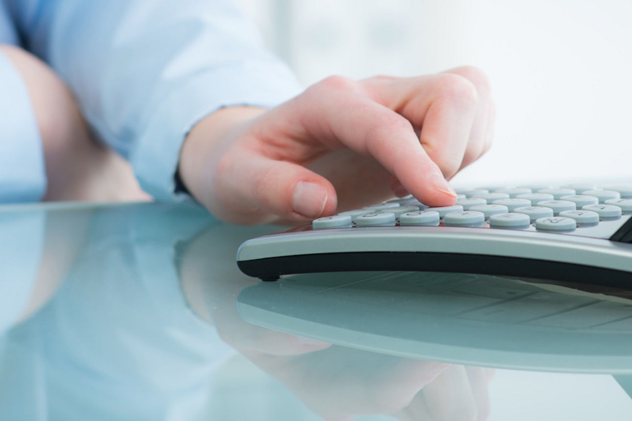 Eine Hand tippt auf einem Taschenrechner