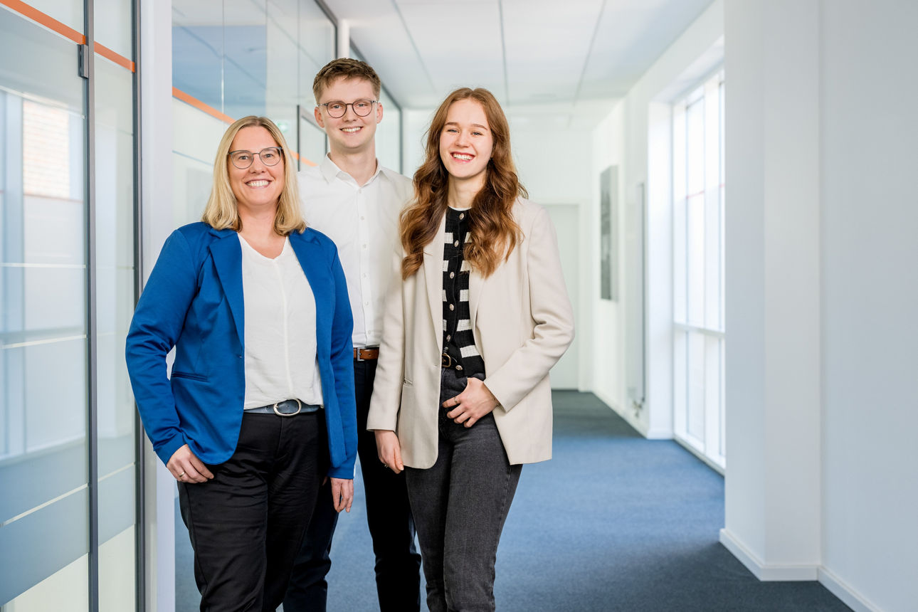 Drei Kollegen schauen in die Kamera.