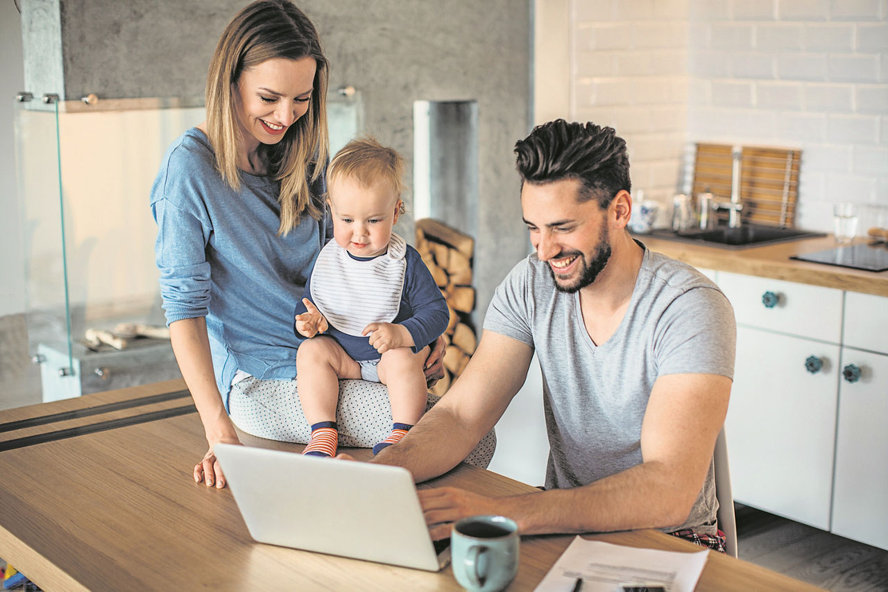 Eine Familie befindet sich in der Küche und schauen auf einem Laptop