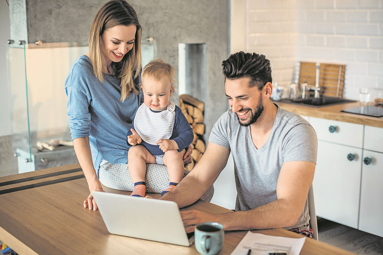 Familie sitzt in der Küche vor einem Laptop