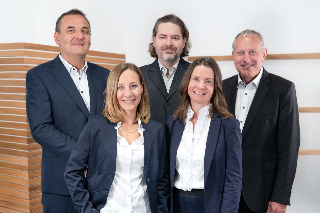 Zwei Männer und zwei Frauen stehen lächelnd nebeneinander