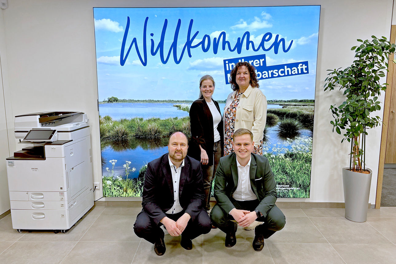 Fünf Mitarbeiterinnen und Mitarbeiter der Raiffeisenbank vor einer Hecke