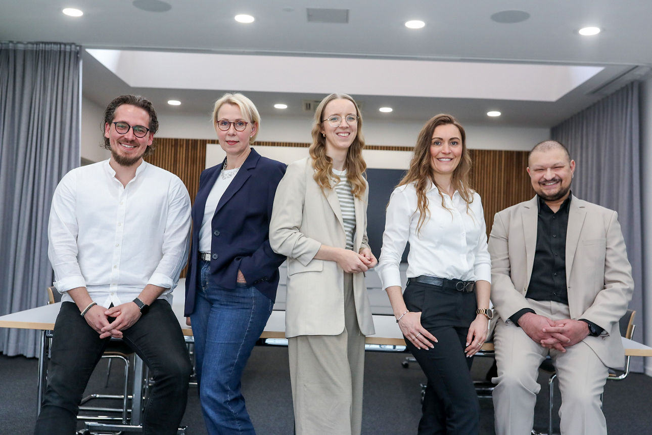 Teamfoto mit fünf Personen die in die Kamera schauen