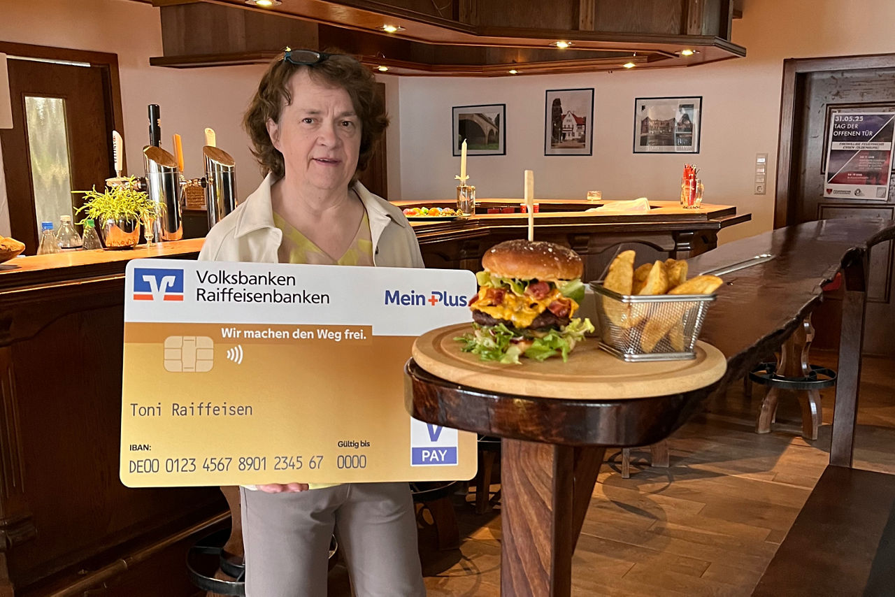 Eine Frau steht in einem Restaurant mit einer Bankkarte in der Hand