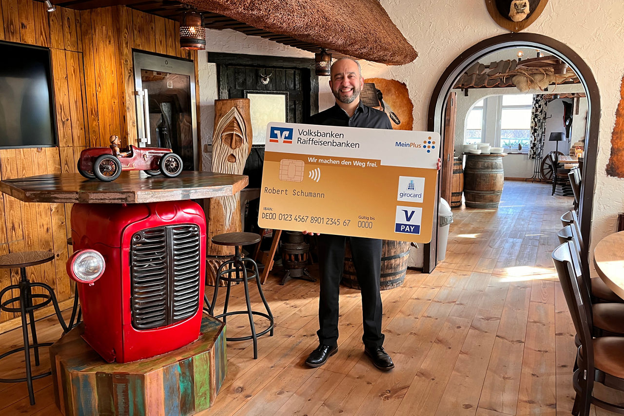 Ein Mann steht in einem Restaurant mit einer Bankkarte in der Hand