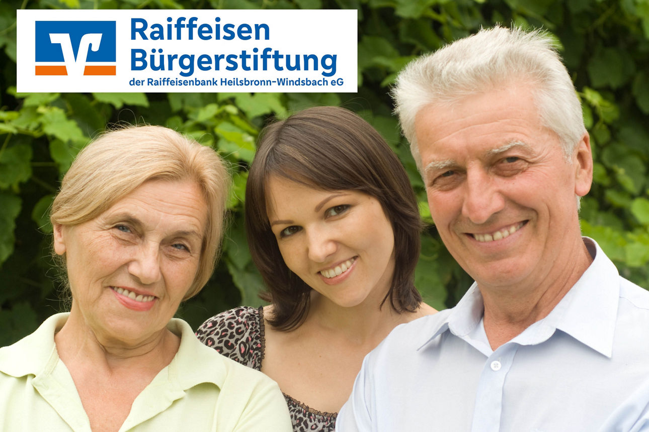 Drei Personen stehen vor einem Gebüsch und lächeln freundlich in die Kamera