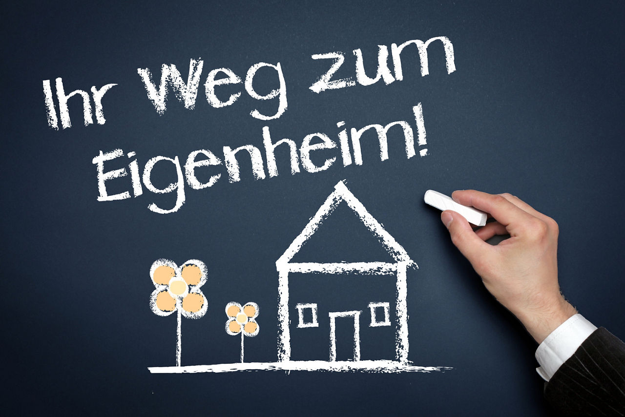 Auf einer Tafel steht: Ihr Weg zum Eigenheim!